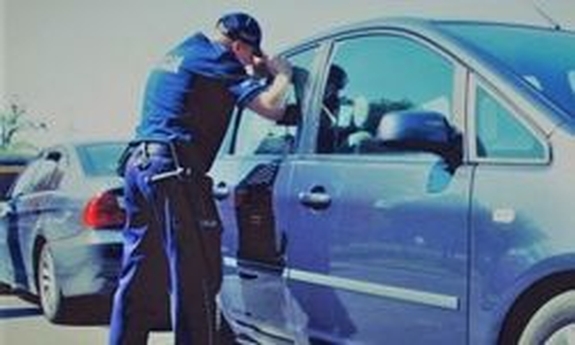 zdjęcie poglądowe policjant przy samochodzie patrzy do środka