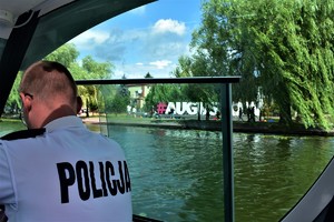 Policjant w łodzi, w tle napis Augustów.