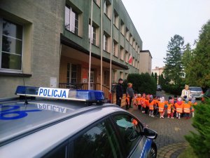 Dzieci wychodzą z policjantem ze szkoły.