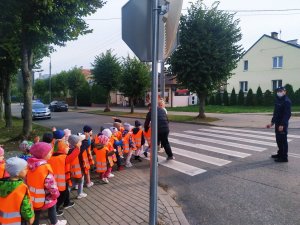 Policjant wstrzymuje ruch, a dzieci przechodzą przez przejście.