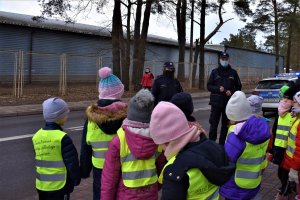 Policjanci tłumaczą dzieciom, jak bezpiecznie przechodzić przez jezdnię.