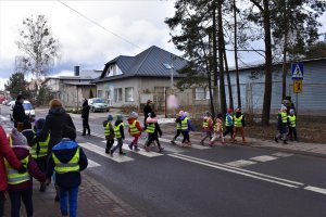 Dzieci przechodzą przez jezdnię pod okiem policjanta.