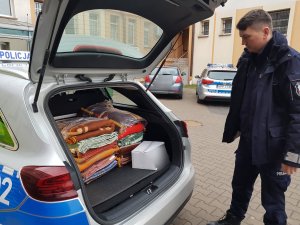 policjant wkłada do bagażnika radiowozu karton z żywnością