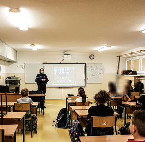 policjantka w sali lekcyjnej prowadzi spotkanie profilaktyczne z młodzieżą dotyczące bezpieczeństwa w sieci