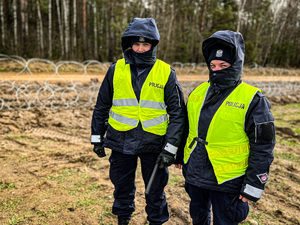 policjantki w kamizelkach odblaskowych z napisem policja stoją wzdłuż  pasa granicznego gdzie rozpoczęła się budowa zapory