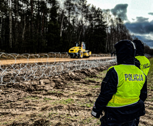 policjantki w kamizelkach odblaskowych z napisem policja stoją wzdłuż  pasa granicznego gdzie rozpoczęła się budowa zapory