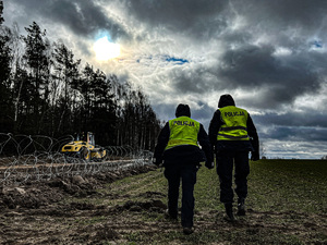 policjantki w kamizelkach odblaskowych z napisem policja idą wzdłuż  pasa granicznego gdzie rozpoczęła się budowa zapory