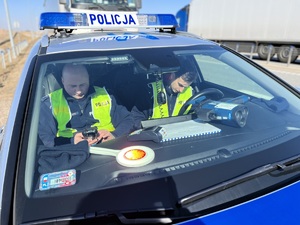 policjanci w radiowozie rozpisują w notatniku przeprowadzone czynności służbowe