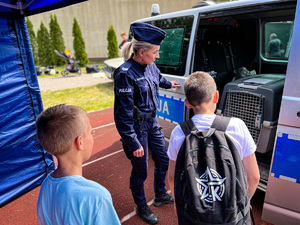 policjantka pokazuje dwóm chłopcom radiowóz
