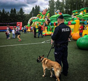 policjant z psem w tle widać dmuchane zjeżdżalnie dla dzieci