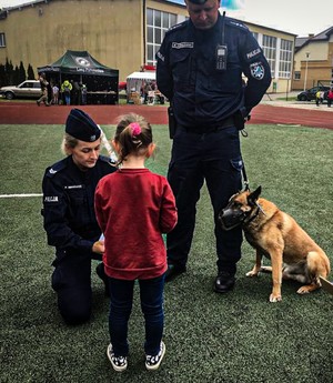 policjantka i policjant z psem rozmawiają z dziewczynką