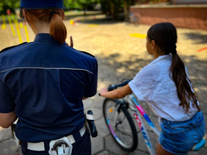 policjantka stoi przy dziewczynce, która siedzi na rowerze