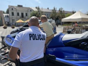 policjant stoi przy skuterze wodnym na którym siedzi dziecko