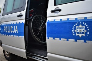 Policyjny radiowóz, w środku rower. Na radiowozie napis pomagamy i chronimy.