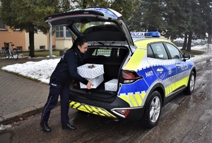 Policjantka wkłada prezenty do samochodu.