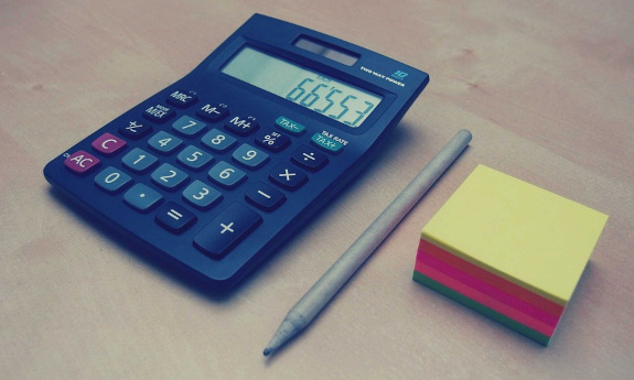 Na zdjęciu kalkulator, notes i długopis.