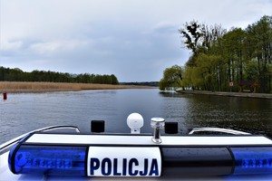 Zdjęcie dachu policyjnej łodzi. W tle jezioro.