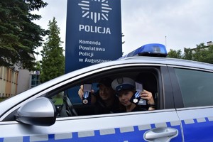 Policjant i policjantka siedzą w radiowozie.