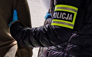 policjant trzyma zatrzymanego za ramię