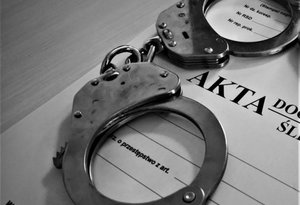 akta sprawy i leżące na nich kajdanki