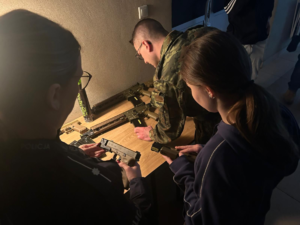 policjantka z strażnikiem granicznym pokazują broń laserową uczennicy