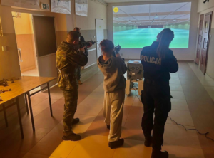 policjantka z strażnikiem granicznym strzelają wraz z uczennicą na strzelnicy laserowej