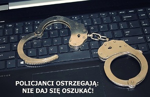 kajdanki leżące na klawiaturze komputera oraz napis "Policjanci ostrzegają: Nie daj się oszukać"