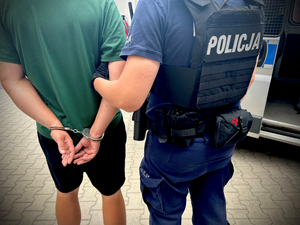 policjant trzymający za ramię sprawcę pobicia matki