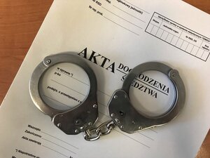 kajdanki leżące na teczce akt sprawy