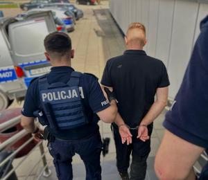 policjant prowadzi zatrzymanego mężczyznę