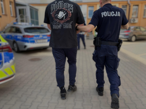 policjant prowadzi zatrzymanego mężczyznę