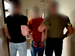 policjanci trzymają za ramiona zatrzymanego